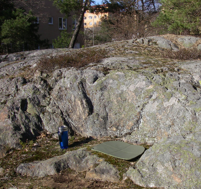 Termosmugg och sittdyna på en solig bergknalle